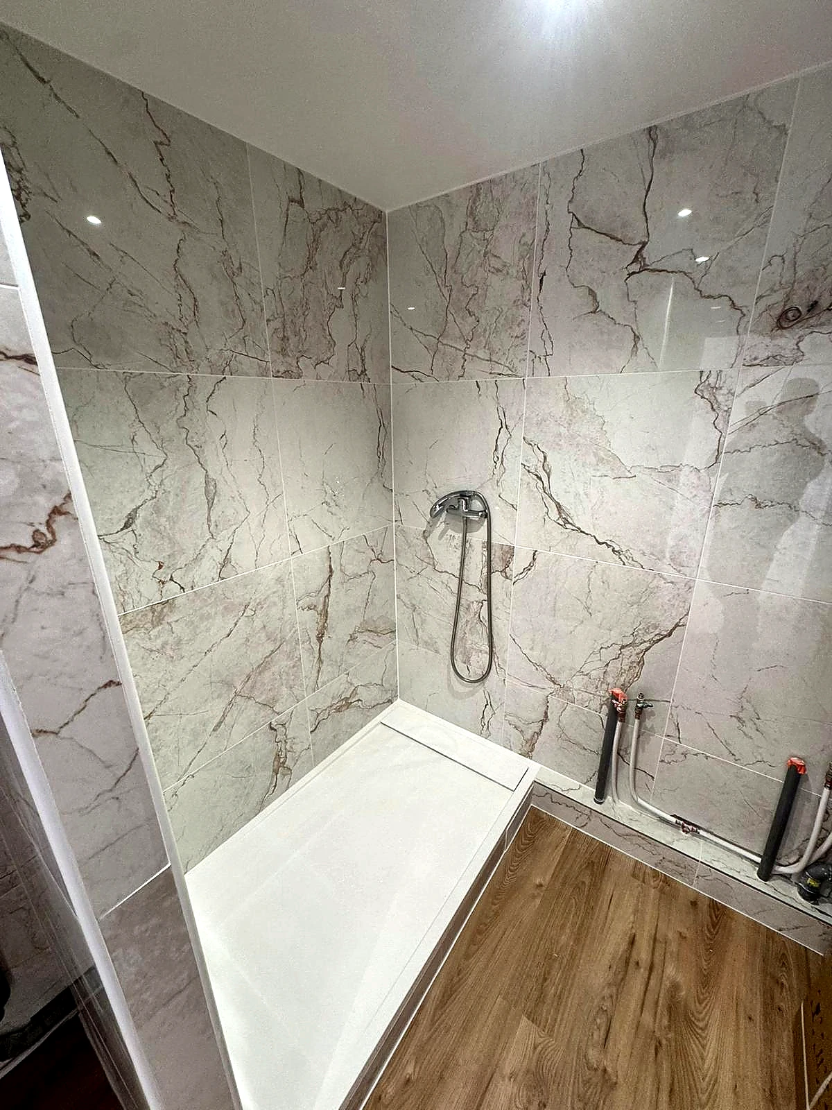 Douche contemporaine avec receveur blanc encastré et revêtement mural effet marbre blanc