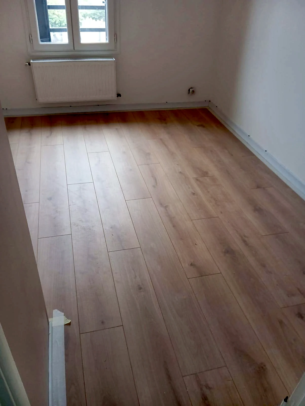 Pièce de vie lumineuse avec parquet chêne clair et murs blancs