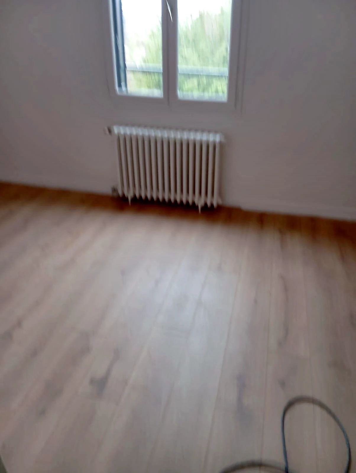Pièce rénovée avec parquet chaleureux et raccordement d'un radiateur sous fenêtre