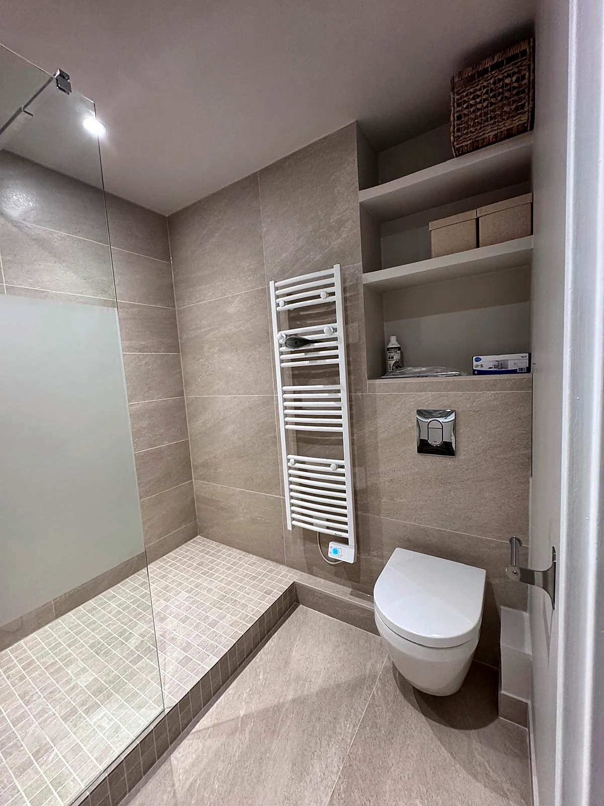 Espace sanitaires avec WC suspendu, rangements intégrés et radiateur sèche-serviettes