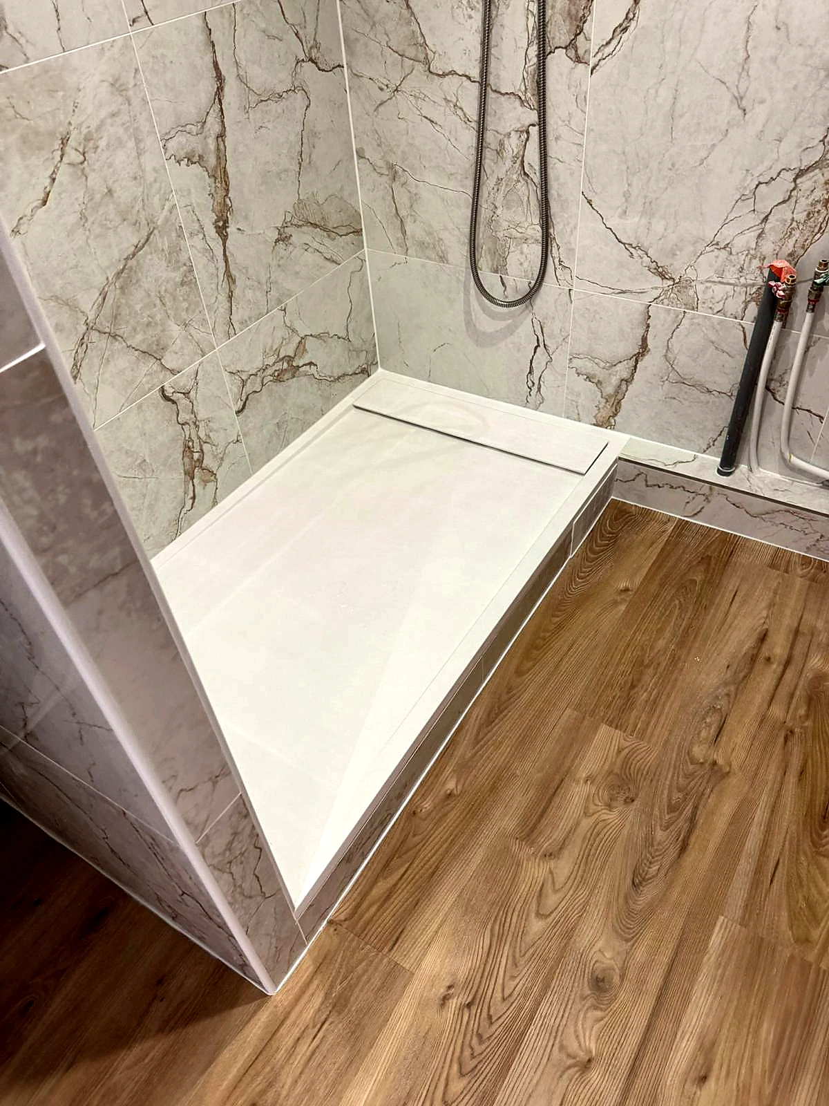 Douche moderne avec receveur blanc encastré et carrelage effet parquet