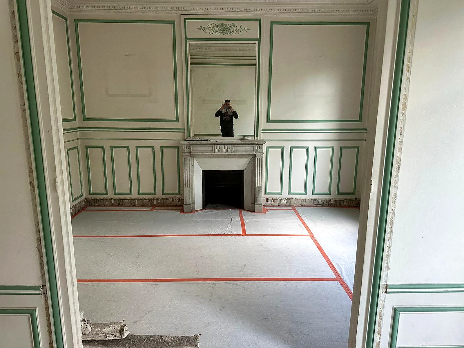 Rénovation intérieure d'une pièce ancienne avec cheminée en marbre, moulures et parquet